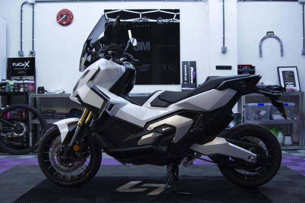 Moto blanca y negra sobre alfombrilla con PPF