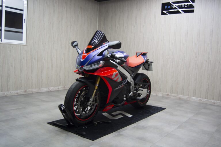 Moto deportiva roja, azul y blanca con carenado vinilado, sobre alfombrilla negra