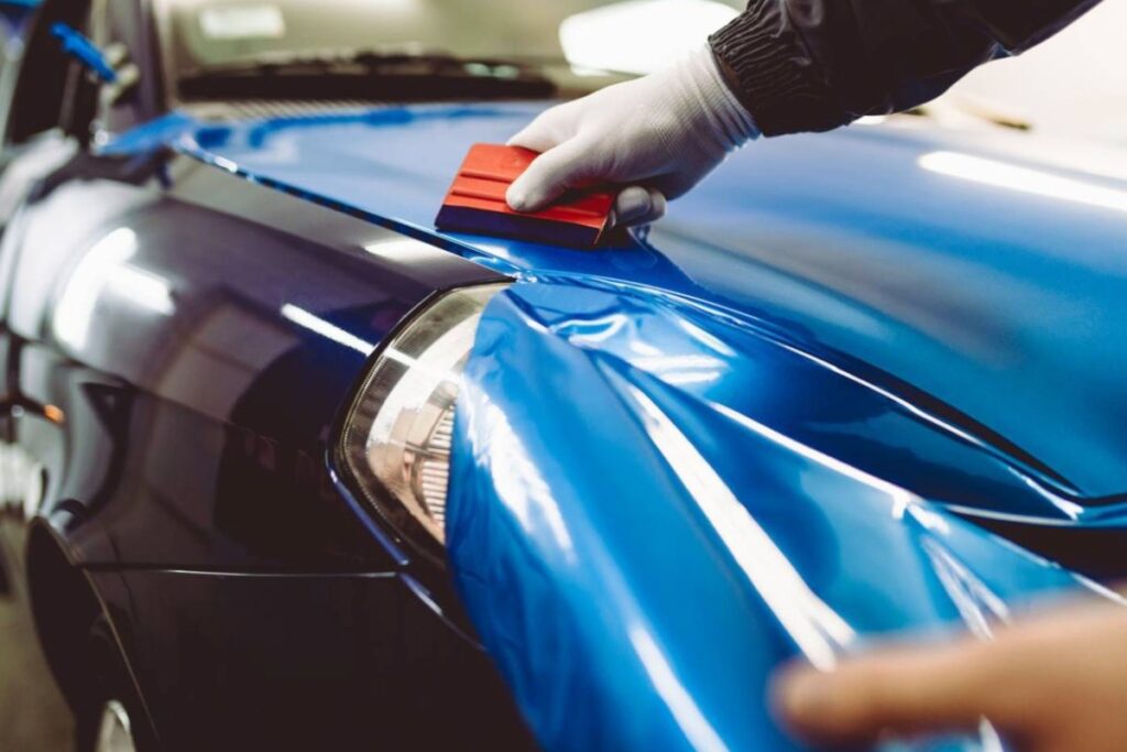 Aplicación de vinilo azul sobre la carrocería de un coche