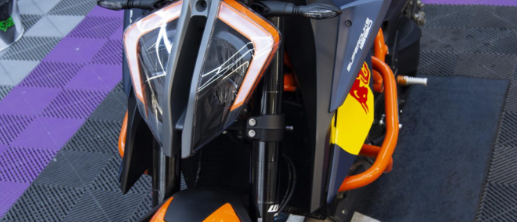 Frontal de moto naranja y negra sobre suelo morado